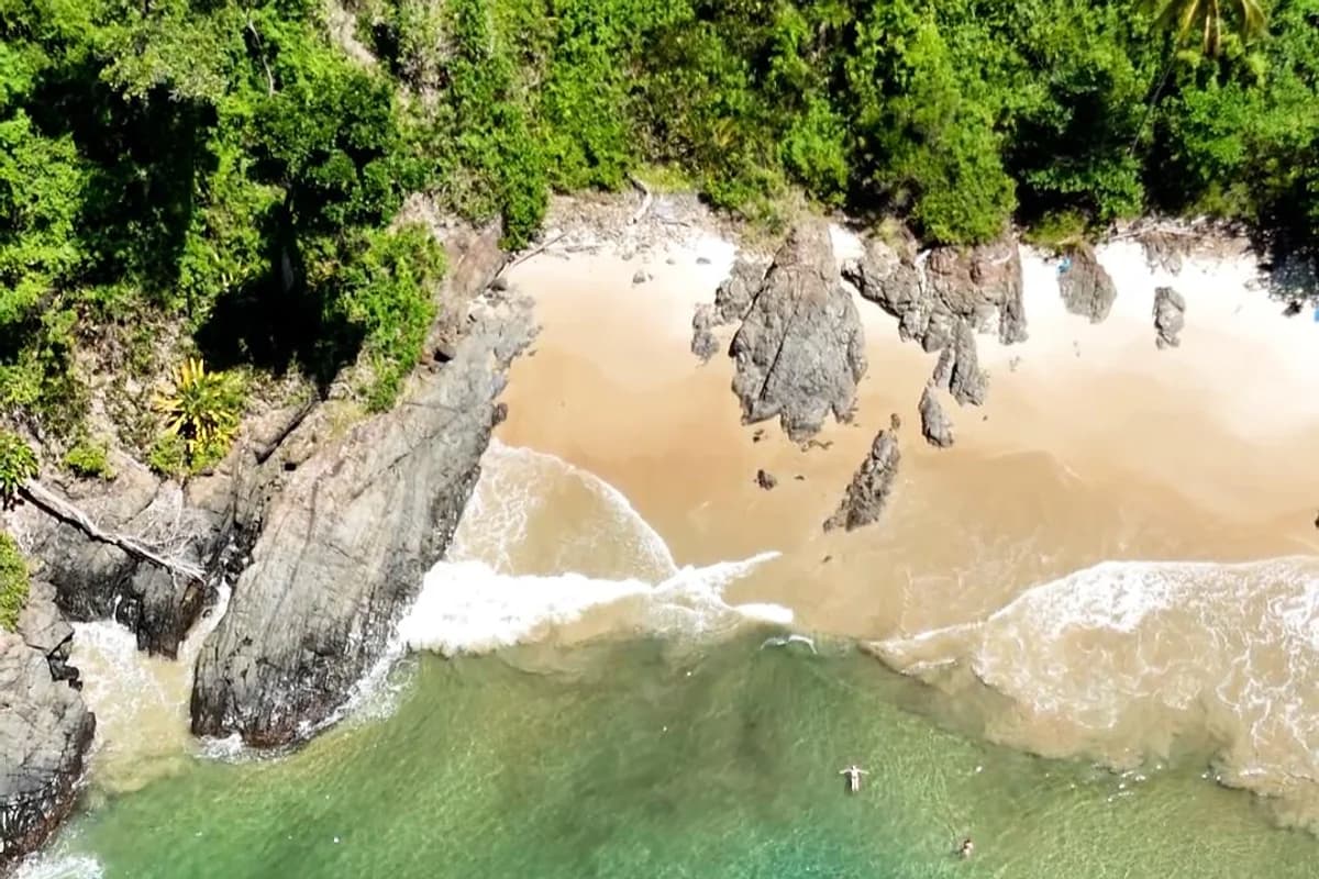 Praia do Siriaco em Itacare cercada por vegetacao e pedras
